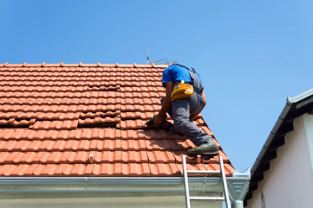 roofing contractor repairs roof depreciation using tools and ladder