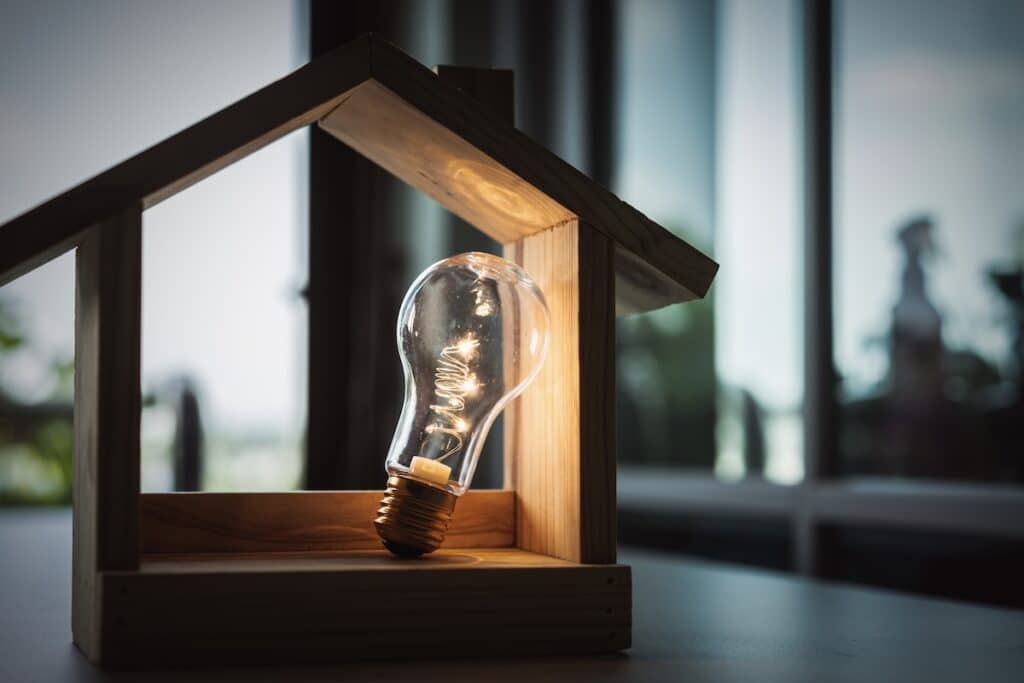 Light bulb with wood house on the table, a symbol for eco lighting