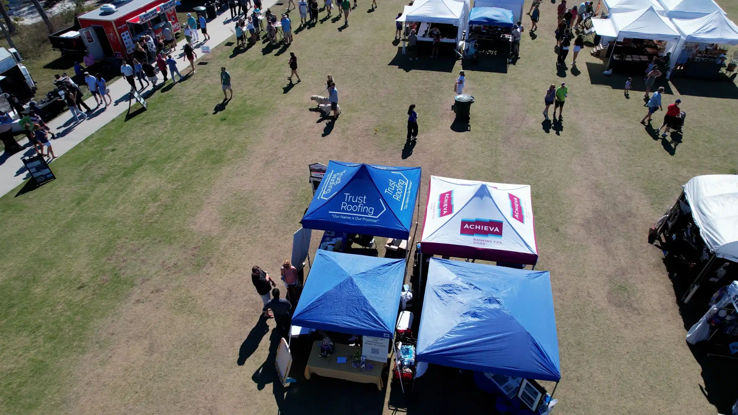 A blue tent that says Trust Roofing at a festival